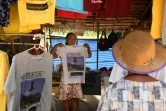 Une vendeuse montre à des touristes un "t-shirt souvenir" du sauvetage des adolescents en 2018 dans la grotte inondée de Tham Luang,  le 13 juin 2019 à Mae Sai, en Thaïlande