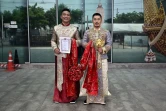 es Chinois Song Jihan (d) et Wang Zengyi montrent le certificat d'enregistrement de leur mariage devant un bureau de district à Bangkok, le 29 mai 2025 en Thaïlande