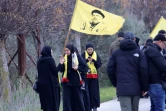 Des habitantes de Kfar Kila portant un drapeau représentant le chef défunt du Hezbollah, tué par Israël, se rassemblent à Borj El Mlouk, dans le sud du Liban, sur une route barrée par l'armée israélienne, le 26 janvier 2025