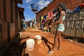 Une femme remplit des seaux d'eau dans une ruelle de Santa Luzia, près de Brasilia, le 3 août 2020 au Brésil