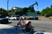 Une femme et sa fille de 2 ans dans une poussette devant une pompe à pétrole le 21 octobre 2019 à Signal Hill, en Californie 