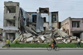 Des habitants passent devant des bâtiments en ruine à Okhtyrka, le 1er août 2022 en Ukraine