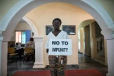 Ayesha Hamun Jammeh, à Banjul le 19 avril 2022, pose avec un panneau "Non à l'impunité", réclamant justice pour son père et sa tante, tués présumément par le régime de l'ex-président Yahya Jammeh en Gambie