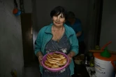 Une habitante tient un plat de galettes de pomme de terre qu'elle a préparées dans un sous-sol servant d'abri, le 30 juin 2022 à Seversk, dans la région de Donetsk, en Ukraine