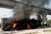 Des habitants de Rawalpindi (Pakistan) passents aux abords de fourgons pénitentiaires incendiés par des manifestants islamistes samedi 25 novembre 2017