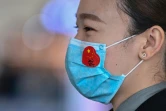 Un employé de l'aéroport de Wuhan porte un masque de protection avec un sticker du drapeau chinois, au jour où s'achève un long bouclage à cause du coronavirus, le 8 avril 2020