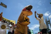 A Manille, le 8 septembre 2018, un manifestant habillé en dinosaure tient une pancarte "Go Fossil-free" ("Finissons-en avec les énergies fossiles"), au cours d'une manifestation dans le cadre de la journée mondiale "Rise for Climate" (Debout pour le climat)