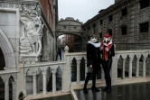 Des artisans vénitiens portant des masques et costumes de carnaval posent près du pont des Soupirs, le 7 février 2021 à Venise (Italie)