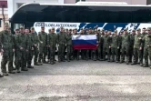 Image tirée d'une vidéo diffusée par le ministère russe de la Défense, le 9 juin 2025, de prisonniers de guerre russes tenant un drapeau russe devant un bus après un échange dans un lieu non divulgué au Bélarus