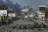 Habitants d'Irpin marchant à côté d'un cadavre pour évacuer la ville, le 10 mars 2022 en Ukraine