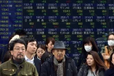 Des piétons devant un écran de cotation à Tokyo le 7 janvier 2016
