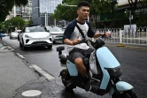 Un robotaxi (g), véhicule autonome sans chauffeur, du projet "Apollo Go" du géant technologique chinois Baidu, dans une rue de Wuhan, le 1er août 2024 dans la province chinoise du Hubei