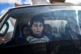 Un enfant syrien regarde depuis une voiture des civils en train de fuir la ville d'Afrine dans le nord-est de la Syrie, le 17 mars 2018 