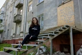 La reporter de guerre ukrainienne, Alina Yevych, assise sur les marches d'un bâtiment endommagé à Kramatorsk, dans la région de Donetsk, le 11 mai 2025