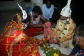 Un prêtre hindou effectue des rituels pour un couple nouvellement marié alors qu'ils portent des masques dans un temple hindou à Siliguri le 28 juillet 2020