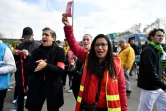 Une militante de la CGT brandit un "carton rouge à la retraite à 64 ans" à la sortie du métro à Saint-Denis, près de Paris, le 29 avril 2023