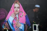 Un homme nettoie un cliché de la photographe afghane Fatimah Hossaini exposé le 3 juin 2022 à La Gacilly (Morbihan) dans le cadre de la 19e édition du festival photo en plein air de la commune
