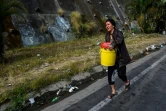 Une femme porte un seau rempli d'eau pour l'utiliser dans ses toilettes, le 1er avril 2019 à Petare, un quartier de Caracas, au Venezuela