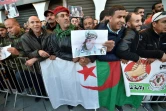 Des Algériens se rassemblent avec le drapeau national et des portraits de l'ancien chef militaire algérien, le général Ahmed Gaïd Salah, devant le Palais du Peuple en prévision de ses funérailles à Alger le 25 décembre 2019