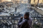 Une femme à son balcon devant des maisons et magasins incendiés après une explosion de gaz dans le quartier d'Embakasi à Nairobi, le 2 février 2024
