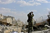 Un soldat syrien photographie les décombres d'un bâtiment faisant partie d'un centre de recherches dans le nord de Damas visé par des frappes américaines, françaises et russes en représailles à une attaque chimique présumée, le 14 avril 2018, lors d'une visite organisée par le ministère syrien de l'Information