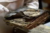 Le père Najeeb Michaeel montre un ancien manuscrit très endommagé au Centre de numérisation des manuscrits orientaux (CNMO) à Erbil, dans le nord de l'Irak, le 1er mars 2018 