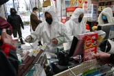 Des employés en pharmacie, en combinaison et masque de protection, servent des clients, le 25 janvier 2020 à Wuhan, épicentre du nouveau coronavirus