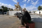 Un Tunisien lit le journal devant la sculpture de la cariole de M. Bouazizi, le 27 octobre 2020 à Sidi Bouzid