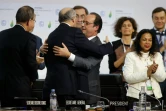 Le ministre français des Affaires étrangères Laurent Fabius (2eG) et le président François Hollande s'enlacent à Paris le 12 décembre 2015