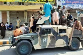 Des talibans et des civils sur un véhicule ayant appartenu à l'armée afghane, le 15 août 2021 dans la province de Laghman