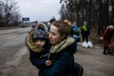 Une femme avec son enfant dans les bras quitte la ville d'Irpin, au nord-ouest de Kiev, le 7 mars 2022.

