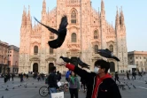 Un homme au visage couvert d'un masque protecteur joue avec des pigeons devant la cathédrale de Mialn en Italie, le 24 février 2020