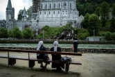 Des pèlerins devant la basilique Notre-Dame du Rosaire avant la réouverture du sanctuaire de Lourdes, fermé pour la première fois de son histoire pendant deux mois, pour cause d'épidémie, le 16 mai 2020 à Lourdes