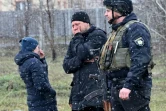 Des personnes se tiennent près d'une fosse commune dans la localité ukrainienne de Boutcha (nord-ouest de Kiev), le 3 avril 2022 
