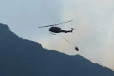 Un hélicoptère transportant un paquet d'eau pour lutter contre un incendie le 18 avril 2021 au pied de Table Mountain, près de l'Université du Cap, en Afrique du Sud