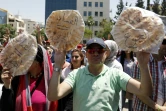 Des Jordaniens brandissent du pain sur lequel est écrit "corruption = faim" lors d'une manifestation contre l'austérité et la cherté de la vie, le 6 juin à Amman
