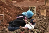 Une femme se recueille sur la tombe d'un proche décédé du Covid-19 dans un cimetière de Bekasi (Indonésie) le 28 janvier 2021.