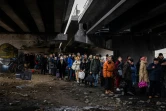Des habitants attendent leur tour pour traverser un pont détruit pour quitter la ville d'Irpin, au nord-ouest de Kiev, le 7 mars 2022.