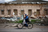 Un homme à vélo passe devant une maison détruite dans le village ukrainien de Derhachi, au nord de Kharkiv, dans l'est de l'Ukraine, le 27 avril 2022