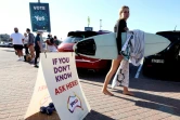 Une surfeur passe près d'un bureau de vote à Bondi Beach à Sydney le 14 octobre 2023