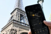 Une personne près de la Tour Eiffel tient son smartphone indiquant la température de 42 degrés Celsius, le 25 juillet 2019 à Paris
