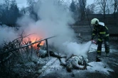 Un pompier éteint les corps carbonisés de passants tués par une frappe russe sur la tour de télévision de Kiev, le 1er mars 2022