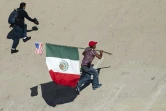 Un migrant portant les drapeaux mexicain et étatsunien tente de passer la frontière entre le Mexique et les Etats-Unis le 25 novembre 2018 à Tijuana