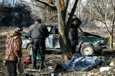 Des habitants près du corps d'un homme tué dans un bombardement, le 24 février 2022 à Tchouhouïv, dans l'est de l'Ukraine