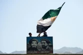 Des Afghans agitent un drapeau afghan au-dessus du portrait du commandant Massoud, dans la vallée du Panchir, le 23 août 2021