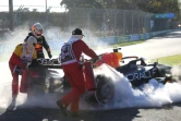 Le pilote de Formule Un Max Verstappen (g) à côté de sa monoplace en feu après son abandon au Grand Prix d'Australie, le 10 avril 2022 à Melbourne
