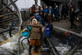 Un homme aide une femme  à traverser un pont détruit pour quitter la ville d'Irpin, au nord-ouest de Kiev, le 7 mars 2022.