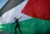 Un jeune homme pose devant le drapeau palestinien le 12 octobre 2017 dans la ville de Gaza