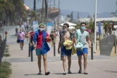 Des promeneurs avec les masques le long de la plage à Barcelone, le 18 juillet 2020