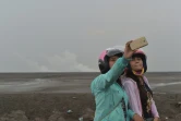 Des touristes prennent des selfies le 28 mars 2016 devant le volcan de boue qui a dévasté  Sidoarjo sur l'île de Java, en Indonésie